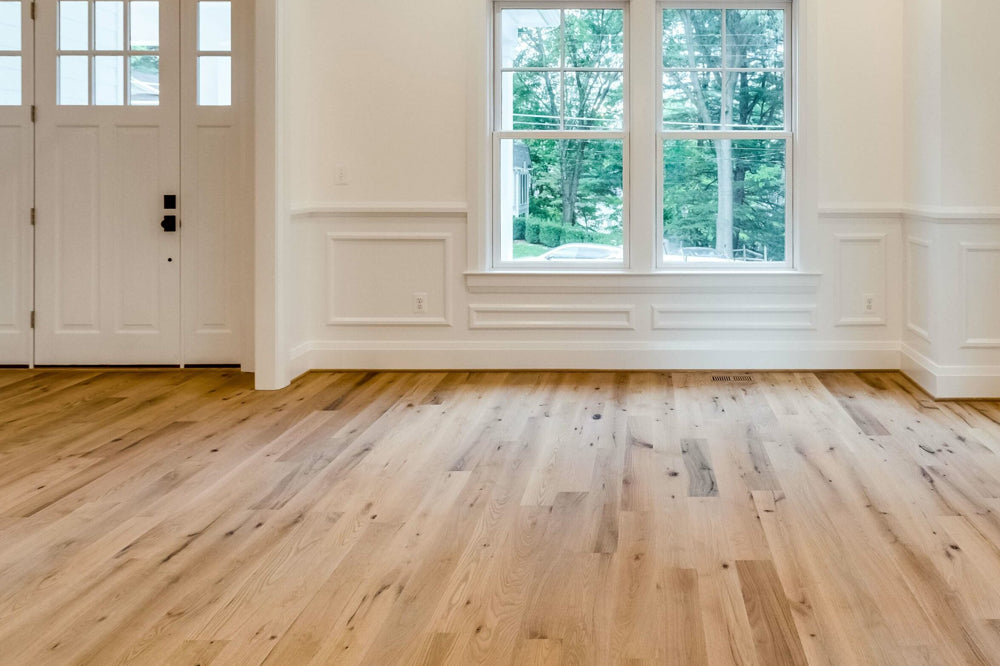 Solid Live Sawn Red Oak Flooring — wide plank hardwood installed in a bright living room with large windows, rustic grain character